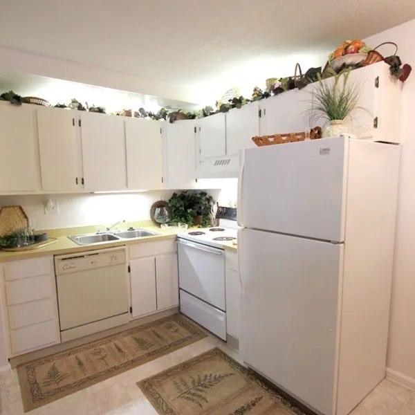 Apartment kitchen with white cabinets, dishwasher, electric range and refrigerator