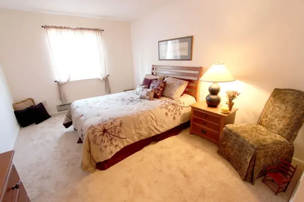 Bedroom with a made bed, bedside lamp and window